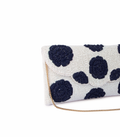 White clutch bag with navy blue polka dot pattern on a white background